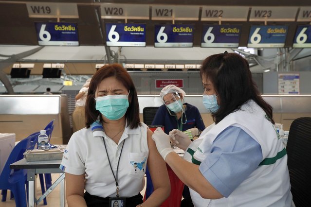 A Thai airport staff member reacts as she receives a shot of COVID-19 CoronaVac vaccine during a COVID-19 vaccination drive for aviation-related personnel at a check-in row in Suvarnabhumi Airport, Samut Prakan province, Thailand, 28 April 2021. Amid the slowdown of air traveling, the Suvarnabhumi Airport allocated the empty check-in rows in the departure hall to service an inoculation drive against COVID-19 for airport's staff members, frontline workers and aviation-related personnels aimed to boost the confidence ahead the reopening of the country for tourists as well as to contain the third wave of the COVID-19 pandemic which has infected thousands of people and claimed 15 lives in Thailand so far. (Photo by Rungroj Yongrit/EPA/EFE)