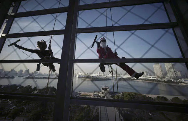 Window cleaners dressed as Santa Claus and a reindeer pose for photographers while cleaning windows at a shopping mall in Tokyo's Daiba bay area, Wednesday, December 21, 2016. (Photo by Eugene Hoshiko/AP Photo)