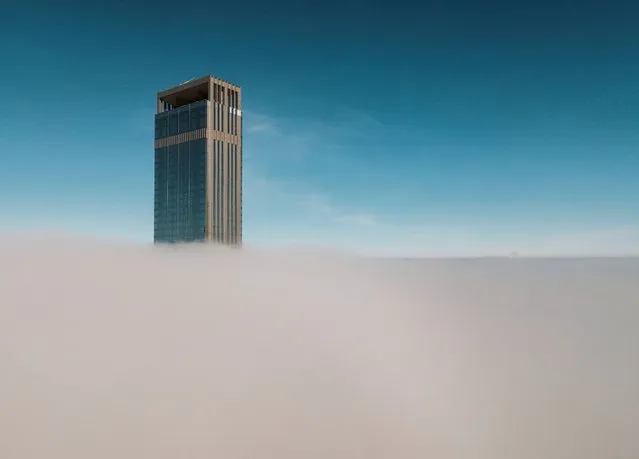 A tower of Abu Dhabi Plaza sticks out of a blanket of thick fog in Astana, Kazakhstan on March 24, 2023. (Photo by Turar Kazangapov/Reuters)
