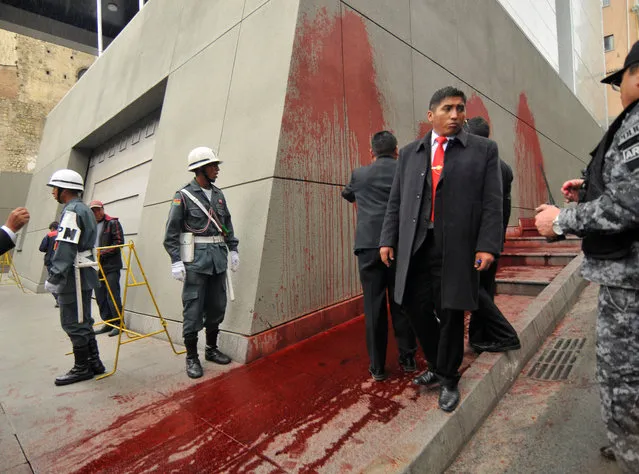 Bolivian presidential guards stand near the site where feminist group Mujeres Creando threw red paint onto the wall of Bolivia's presidential palace, La Casa Grande del Pueblo to protest against President Evo Morales in La Paz, Bolivia on November 27, 2018. (Photo by Claudia Morales/Reuters)