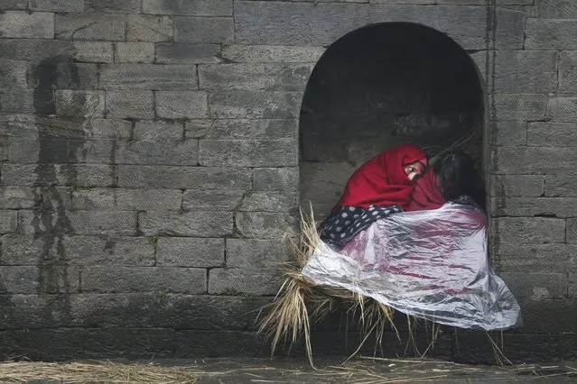 Nepalese Hindu women cover themselves with plastic sheet and take cover as it rains during Swasthani Bratakatha festival  in Kathmandu, Nepal, Monday, February 8, 2016. During this festival, devotees recite holy scriptures dedicated to Hindu goddess Swathing and Lord Shiva. Unmarried women pray to get a good husband while those married pray for the longevity of their husbands by observing a month-long fast. (Photo by Niranjan Shrestha/AP Photo)