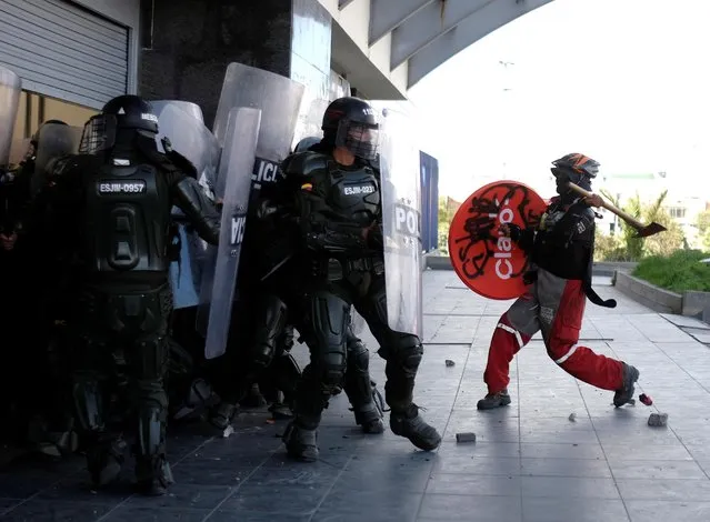 A demonstrator raises an axe towards riot police during anti-government protests, as Colombia commemorates Independence Day, in Bogota on July 20, 2021. (Photo by Santiago Mesa/Reuters)