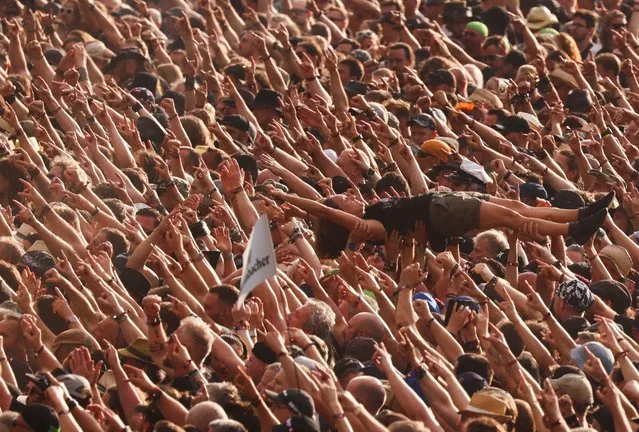 A reveller surfs on top of the crowd during the Wacken Open Air 2022 heavy metal festival in Wacken, Germany on August 4, 2022. (Photo by Thilo Schmuelgen/Reuters)
