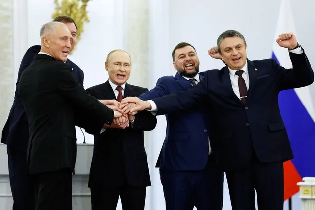 (L-R) The Moscow-appointed heads of Kherson region Vladimir Saldo and Zaporizhzhia region Yevgeny Balitsky, Russian President Vladimir Putin, Donetsk separatist leader Denis Pushilin and Lugansk separatist leader Leonid Pasechnik join hands after signing treaties formally annexing four regions of Ukraine Russian troops occupy, at the Kremlin in Moscow on September 30, 2022. (Photo by Dmitry Astakhov/Sputnik/AFP Photo)