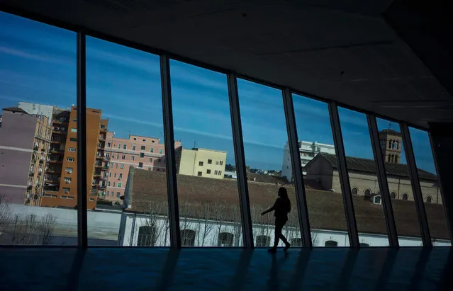 A woman walks by a window wall of the MAXXI  National Museum of the 20th Century Arts overlooking a residential district in Rome, Saturday, February 6, 2016. (Photo by Domenico Stinellis/AP Photo)