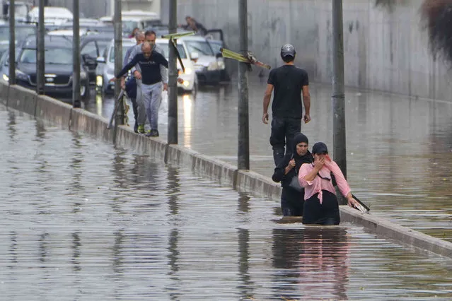 Peope wade through a flooded road after heavy rain in Beirut, Lebanon, Monday, October 16, 2023. (Photo by Bilal Hussein/AP Photo)