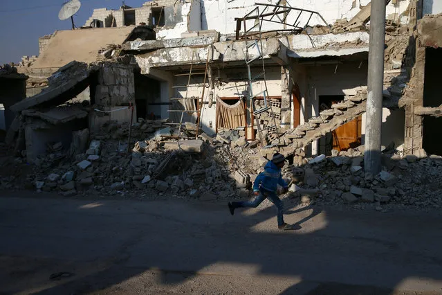 A boy runs near damaged buildings in the rebel held besieged city of Douma, in the eastern Damascus suburb of Ghouta, Syria January 7, 2017. (Photo by Bassam Khabieh/Reuters)