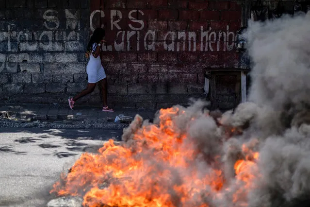 A woman runs past burning tires near a protest demanding the release of political prisoners in front of the Ministry of Justice and Public Security, in Port-au-Prince, Haiti July 29, 2021. (Photo by Ricardo Arduengo/Reuters)