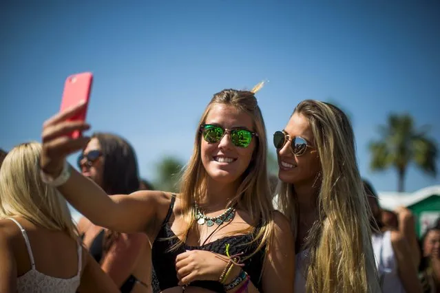 Women take a selfie as they wait in line to enter the Coachella Valley Music and Arts Festival in Indio, California April 11, 2015. (Photo by Lucy Nicholson/Reuters)