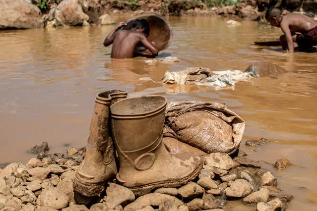 A pair of rubber boots and other tools used in an open pit mine are seen while Venezuelan mining children work through the mud in search of gold in El Callao, Bolivar State, Venezuela, on September 2, 2023. In the town of El Callao, extracting gold from soil starts off as a kid's game, but soon becomes a full-time job that human rights activists says amounts to child exploitation. (Photo by Yris Paul/AFP Photo)