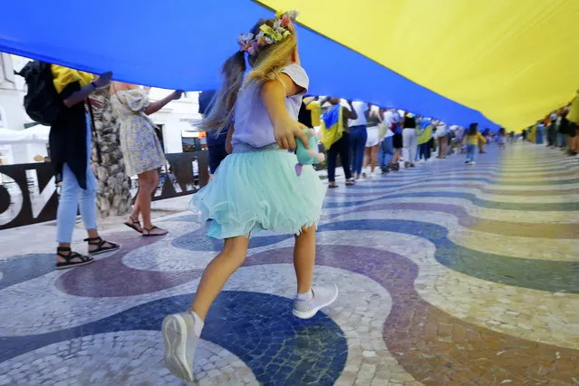 Ukrainian residents in Spain display a 100-meter Ukrainian flag during a protest in Alicante, eastern Spain, 14 October 2022, to condemn the latest shelling in several Ukrainian cities by the Russian army. (Photo by Manuel Lorenzo/EPA/EFE)