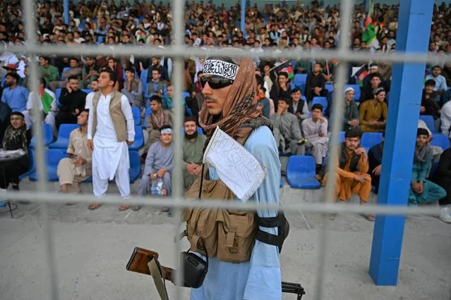 A Taliban fighter (C) keeps vigil as spectators watch the Twenty20 cricket trial match being played between two Afghan teams “Peace Defenders” and “Peace Heroes” at the Kabul International Cricket Stadium in Kabul on September 3, 2021. (Photo by Aamir Qureshi/AFP Photo)