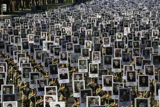 Azerbaijan's Army soldiers carry portraits of the soldiers killed during the fighting over Nagorno-Karabakh in 2020 year, during a memorial event in Baku, Azerbaijan, Monday, September 27, 2021. Azerbaijan and Armenia are marking the first anniversary of the start of their six-week war in which more than 6,600 people died and that ended with Azerbaijan regaining control of large swaths of territory. Soldiers carrying photos of comrades killed in the war marched Monday through the center of the Azerbaijaini capital Baku. (Photo by Aziz Karimov/AP Photo)