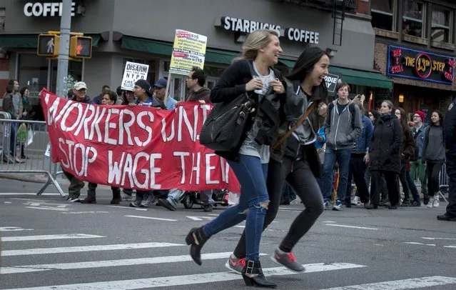 Women cross a street as demonstrators calling for social, economic and racial justice march in New York May 1, 2015. In New York, a crowd of protesters waved banners for Freddie Gray, a black man who suffered severe spinal injuries while in police custody, as part of a larger May 1 International Labor Day demonstration touching on workers rights and wages as well. (Photo by Brendan McDermid/Reuters)