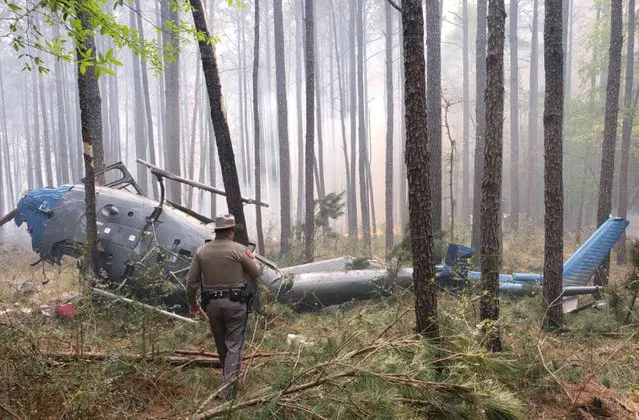 This March 27, 2019 photo provided by the Texas Department of Public Safety shows a TXDPS officer walking near the wreckage of downed helicopter in Montgomery County, about 70 miles (110 kilometers) north of Houston. The U.S. Forest Service says a firefighter from California has died from the crash in the Sam Houston National Forest in Texas. The agency says Daniel Laird was a two-decade veteran of the U.S. Forest Service and was helping with a controlled burn when the helicopter crashed. (Photo by Sgt. Erik Burse/Texas Department of Public Safety via AP Photo)