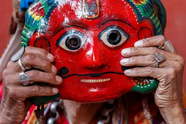 A person adjusts a clay mask while preparing to take part in a deity's procession during the Shikali festival at Khokana, in Lalitpur, Nepal, October 12, 2021. (Photo by Navesh Chitrakar/Reuters)