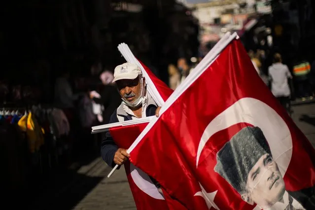 A vendor sells Turkish flags with the portrait of Mustafa Kemal Ataturk, founder of the modern Turkey, in a street market at the Eminonu district in Istanbul, Turkey, Thursday, October 21, 2021. The Turkish lira plunged to a record low against the U.S. dollar Thursday after a harsher than expected cut in interest rates. (Photo by Francisco Seco/AP Photo)