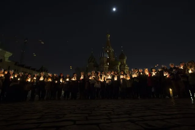 People holding candles mark Earth Hour after the lights are switched off  in front of St. Basil Cathedral on Red Square in Moscow, Russia, Saturday, March 19, 2016. The participants said they also used the event to pay tributes to the victims of the Dubai plane crash in southern Russia that killed all 62 people aboard on Saturday. (Photo by Alexander Zemlianichenko/AP Photo)