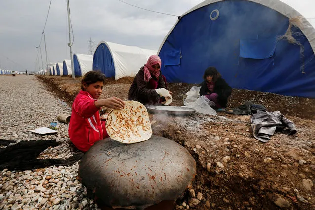 A displaced woman who fled the Islamic State stronghold of Mosul makes bread with their children at Khazer camp, Iraq, Feruary 9, 2017. (Photo by Muhammad Hamed/Reuters)