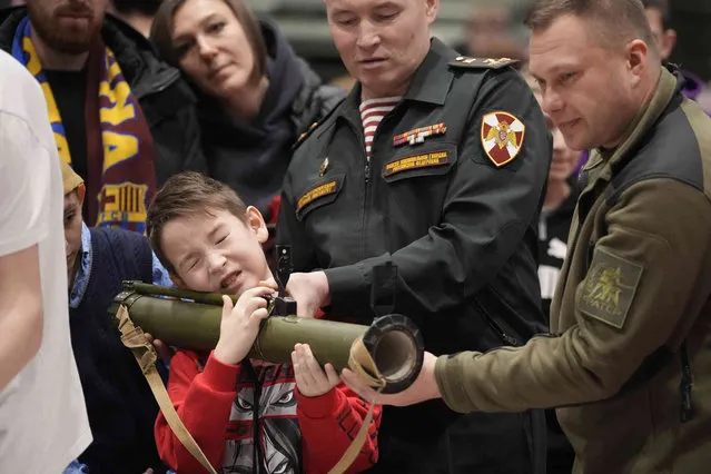A boy holds a training grenade launcher at the 'Russians Change the World' patriotic festival marking Defender of the Fatherland Day in St. Petersburg, Russia, Friday, February 23, 2024. (Photo by Dmitri Lovetsky/AP Photo)