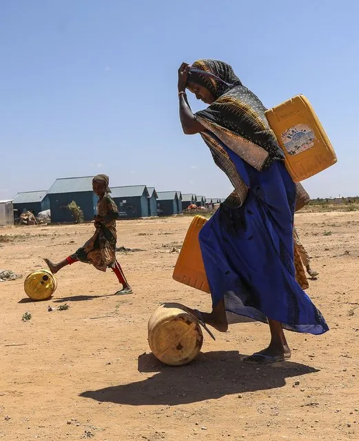 A woman and her children carry jerricans of water on their backs after fetching from one of the water points within the Ladan Internally Displaced Persons (IDP) camp in Ladan, on the outskirts of Dollow, in Jubaland state, Somalia, 30 January 2024 (issued 26 February 2024). The Ladan IDP camp hosts some 5500 households of climate change IDPs.In February 2023, the total number of internally displaced people in Somalia reached 3.8 million, while more than one million had newly been displaced in that year only by May. These people have been forced to leave their homes because of climate change and insecurity, two phenomena that prevent them from going back and make their displacement almost permanent. Abdullahi Halakhe, from the organization Refugees International, told EFE. (Photo by Daniel Irungu/EPA)