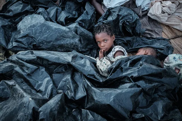 Enia Joaquin Luis, 11, wakes up beside her sister Luisa, 6, under plastic sheets for protect themselves from rain as they stay in shelter at the stands of Ring ground in Buzi, Mozambique, on March 23, 2019. The death toll in Mozambique on March 23, 2019 climbed to 417 after a cyclone pummelled swathes of the southern African country, flooding thousands of square kilometres, as the UN stepped up calls for more help for survivors. Cyclone Idai smashed into the coast of central Mozambique last week, unleashing hurricane-force winds and rains that flooded the hinterland and drenched eastern Zimbabwe leaving a trail of destruction. (Photo by Yasuyoshi Chiba/AFP Photo)