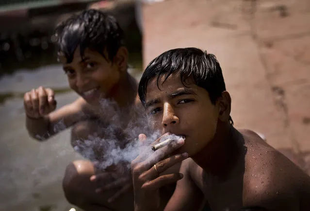 An Indian boy smokes a cigarette after a bath at a public fountain on a summer day in New Delhi, India, Wednesday, May 6, 2015. (Photo by Saurabh Das/AP Photo)