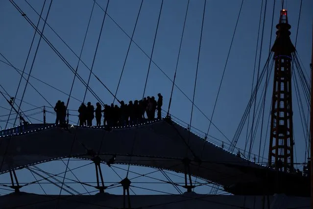 People climb the roof of the O2 Arena in North Greenwich, in London on March 2, 2024. (Photo by Isabel Infantes/Reuters)