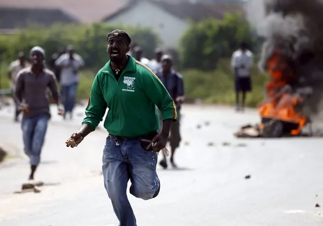 Protesters run to throw stones at policemen near a burning barricade during a protest against Burundi President Pierre Nkurunziza and his bid for a third term in Bujumbura, Burundi, May 21, 2015. (Photo by Goran Tomasevic/Reuters)