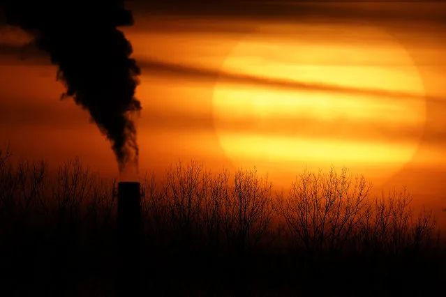 Emissions from a coal-fired power plant are silhouetted against the setting sun, Monday, February 1, 2021, in Kansas City, Mo. (Photo by Charlie Riedel/AP Photo/File)