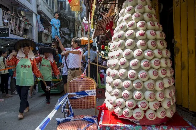 A boy, wearing a protective suit to depict a healthcare worker handling the bird flu, stands above the crowd as his float makes its way past a small bun tower during a Bun Festival parade at Hong Kong's Cheung Chau island, China May 25, 2015. (Photo by Tyrone Siu/Reuters)