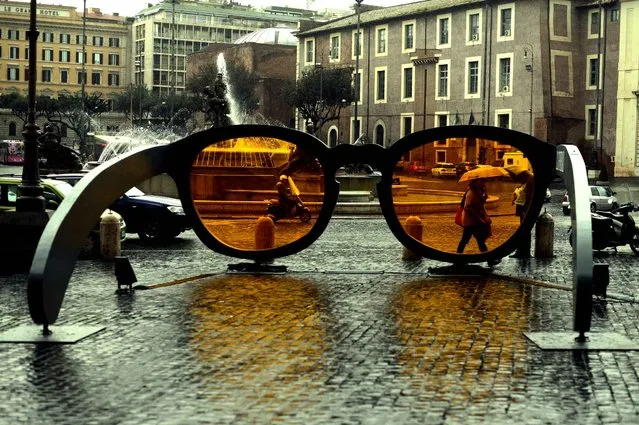 People walk in front of a giant pair of sunglasses installed in central Rome on March 23, 2014. (Photo by Gabriel Bouys/AFP Photo)