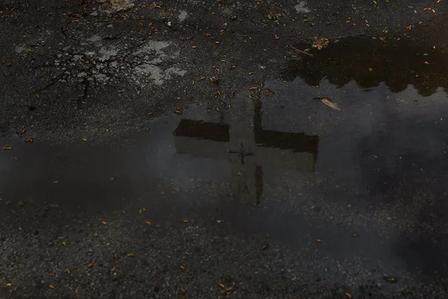 A cross is seen reflected in a puddle of water in Alcazar de San Juan, Spain, April 5, 2016. (Photo by Susana Vera/Reuters)