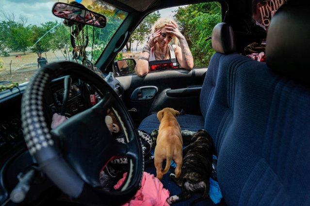 A woman checks on two of her puppies after her neighborhood was evacuated because of severe flooding in Channelview, Texas, on Saturday, May 4, 2024. Days of rain caused rivers to swell, leaving homes and businesses flooded and thousands of people displaced. (Photo by Raquel Natalicchio/Houston Chronicle/AP Photo)