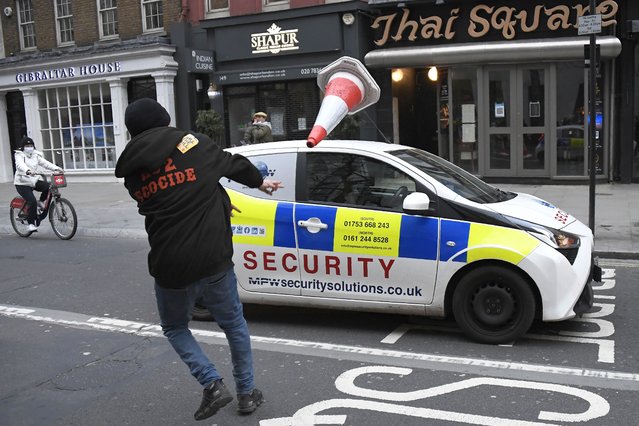A man throws a traffic cone at a car during clashes following a “Kill the Bill” protest in London, Saturday, April 3, 2021. The demonstration is against the contentious Police, Crime, Sentencing and Courts Bill, which is currently going through Parliament and would give police stronger powers to restrict protests. (Photo by Alberto Pezzali/AP Photo)