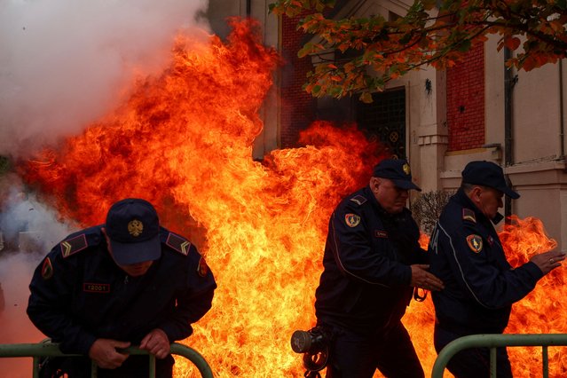 Police officers react as supporters of the opposition hurl Molotov cocktails at the mayor's office, accusing him of corruption, in Tirana, Albania on April 19, 2024. (Photo by Florion Goga/Reuters)