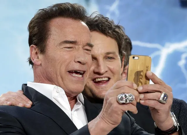 Actors Arnold Schwarzenegger, left, and Jason Clarke take a picture as they arrive for the Europe premiere of the movie 'Terminator: Genisys' in Berlin, Germany, Sunday, June 21, 2015. (AP Photo/Michael Sohn)