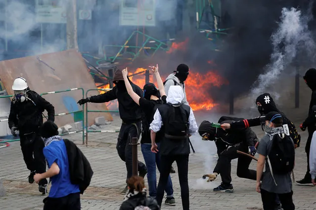 Youths take cover from tear gas during clashes during a demonstration against the French labour law proposal in Nantes, France, as part of a nationwide labor reform protests and strikes, April 28, 2016. (Photo by Stephane Mahe/Reuters)