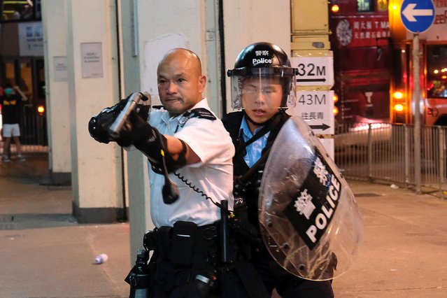A police officer points a gun towards anti-extradition bill protesters who surrounded a police station where detained protesters are being held during clashes in Hong Kong, China July 30, 2019. Hundreds of people surrounded a police station in Hong Kong chanting free the martyrs after 44 activists were charged with rioting following weekend clashes between protesters and police defending China s representative office. (Photo by Tyrone Siu/Reuters)