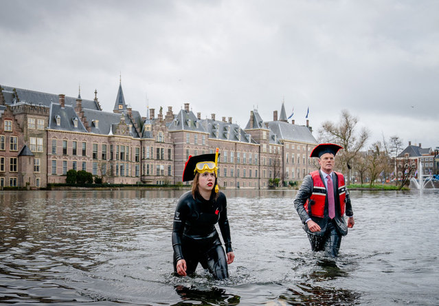 Activists leave after bathing in the Hofvijver lake in the Hague, on April 6, 2021 during a demonstration to indicate that science is all about water. Professors, students, staff and administrators of Dutch universities hope to convince politicians to invest in academic education and research.  (Photo by Bart Maat/ANP/AFP Photo)