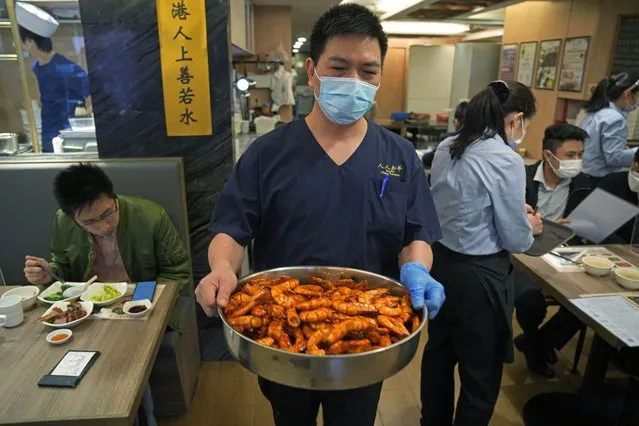 Poon Choi Chef Fong Wah-yat carries a bucket of prawns while making the “Poon Choi” dish at the RenRen Heping Restaurant in Hong Kong on January 21, 2022. (Photo by Kin Cheung/AP Photo)