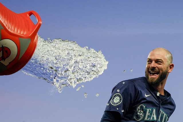 Seattle Mariners' Mitch Haniger tries to avoid a dousing during the celebration of the team's 2-1 win over the Chicago White Sox in 10 innings in a baseball game Wednesday, June 12, 2024, in Seattle. Haniger drove in the winning run. (Photo by Lindsey Wasson/AP Photo)