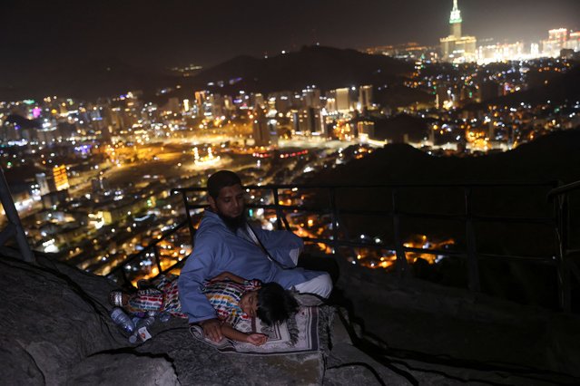 A Muslim pilgrim sits with a child at Mount Al-Noor, where Muslims believe Prophet Mohammad received the first words of the Koran through Gabriel in the Hira cave, ahead of the annual haj pilgrimage, in the holy city of Mecca, SSaudi Arabia, on June 11, 2024. (Photo by Saleh Salem/Reuters)