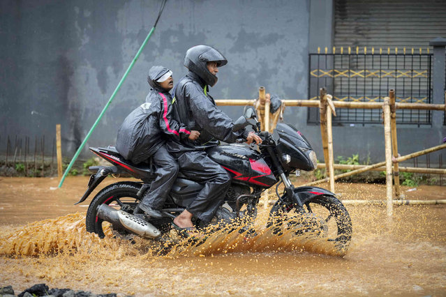 A man takes his son to the school through a flooded street after heavy monsoon rains in Guwahati, India, Wednesday, June 5, 2024. Monsoon has arrived early in north eastern states of India. (Photo by Anupam Nath/AP Photo)