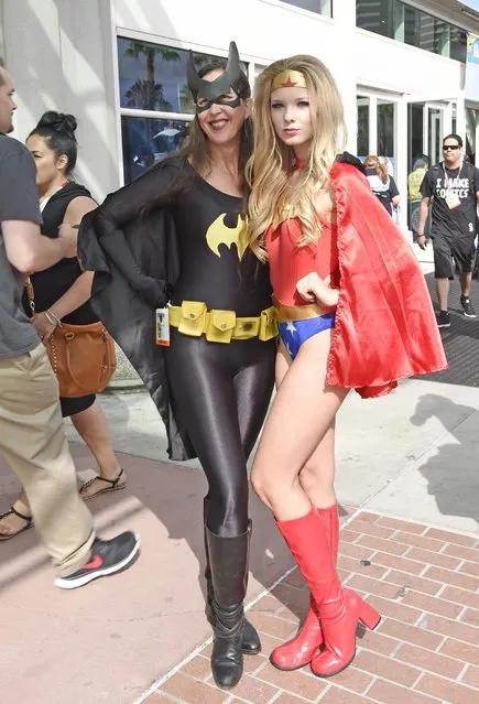 Fans dressed as Batwoman, left, and Wonder Woman pose for photographers in front of the convention center on the first day of the 2015 Comic-Con International at the San Diego Convention Center Thursday, July 9, 2015 in San Diego. Comic-Con runs from July 9-12.  (Photo by Denis Poroy/Invision/AP Photo)