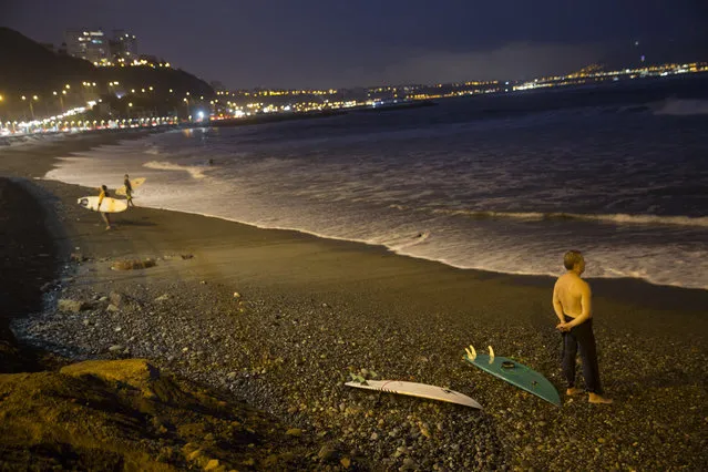 In this April 21, 2017 photo, a man looks out at the Pacific Ocean from the shore at La Pampilla beach in Lima, Peru. Pampilla is the second beach in Latin America that is set up for night surfing. (Photo by Rodrigo Abd/AP Photo)