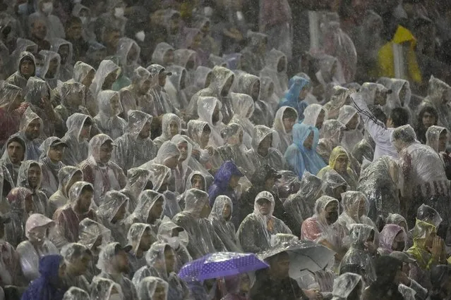 Paraguay fans cover themselves from the rain during a qualifying soccer match against Ecuador for the FIFA World Cup Qatar 2022 at Antonio Aranda stadium in Ciudad del Este, Paraguay, Thursday, March 24, 2022. (Photo by Jorge Saenz/AP Photo)