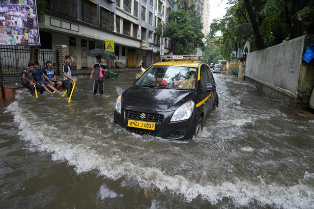 A car drives through a flooded street after heavy rainfall in Mumbai, India, Monday, July 8, 2024. (Photo by Rafiq Maqbool/AP Photo)