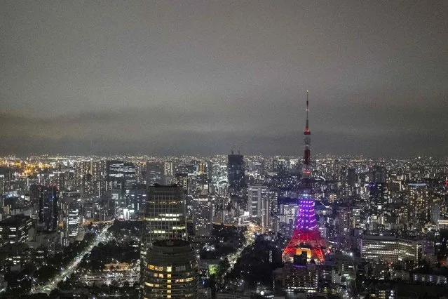 The Tokyo Tower is seen partially lit as part of energy-saving measures following a government electricity supply warning for the capital and surrounding areas, in Tokyo on March 22, 2022. (Photo by Charly Triballeau/AFP Photo)