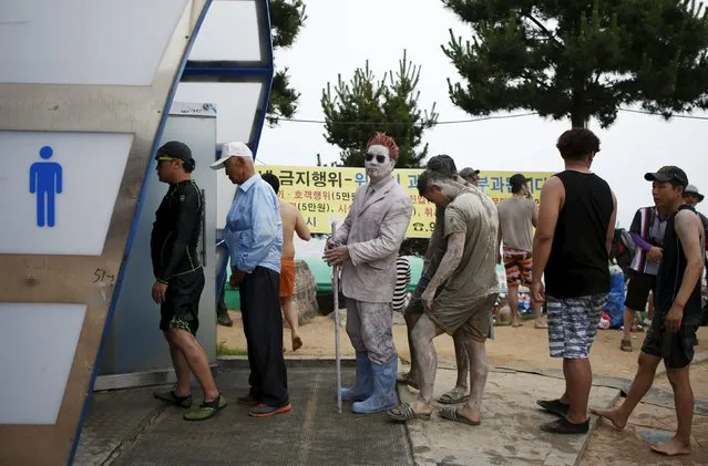 A tourist (C) covered with mud waits in a line to use toilet during the Boryeong Mud Festival at Daecheon beach in Boryeong, South Korea, July 18, 2015. (Photo by Kim Hong-Ji/Reuters)